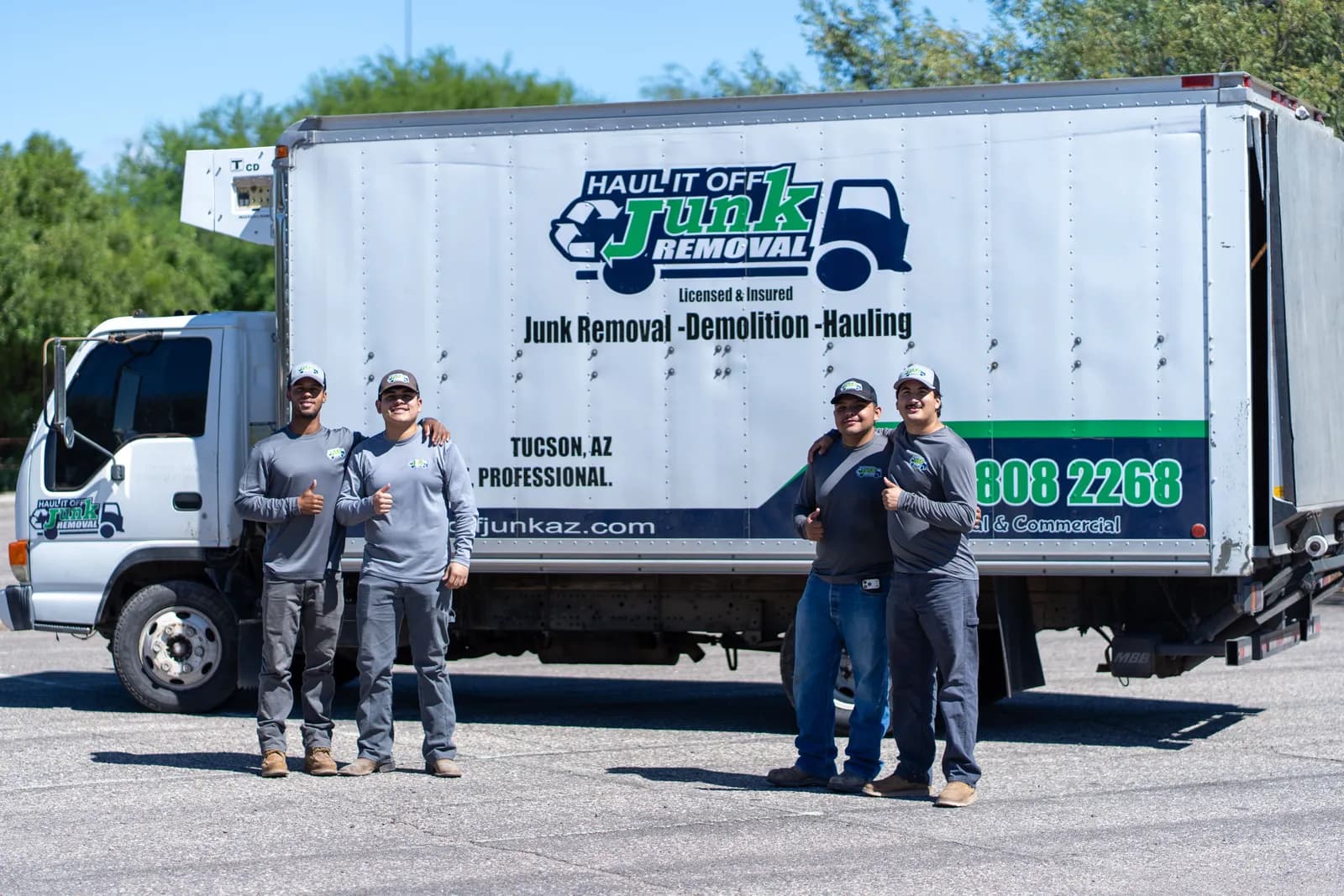Four Haul It Off crew members standing in front of the company box truck in Tucson