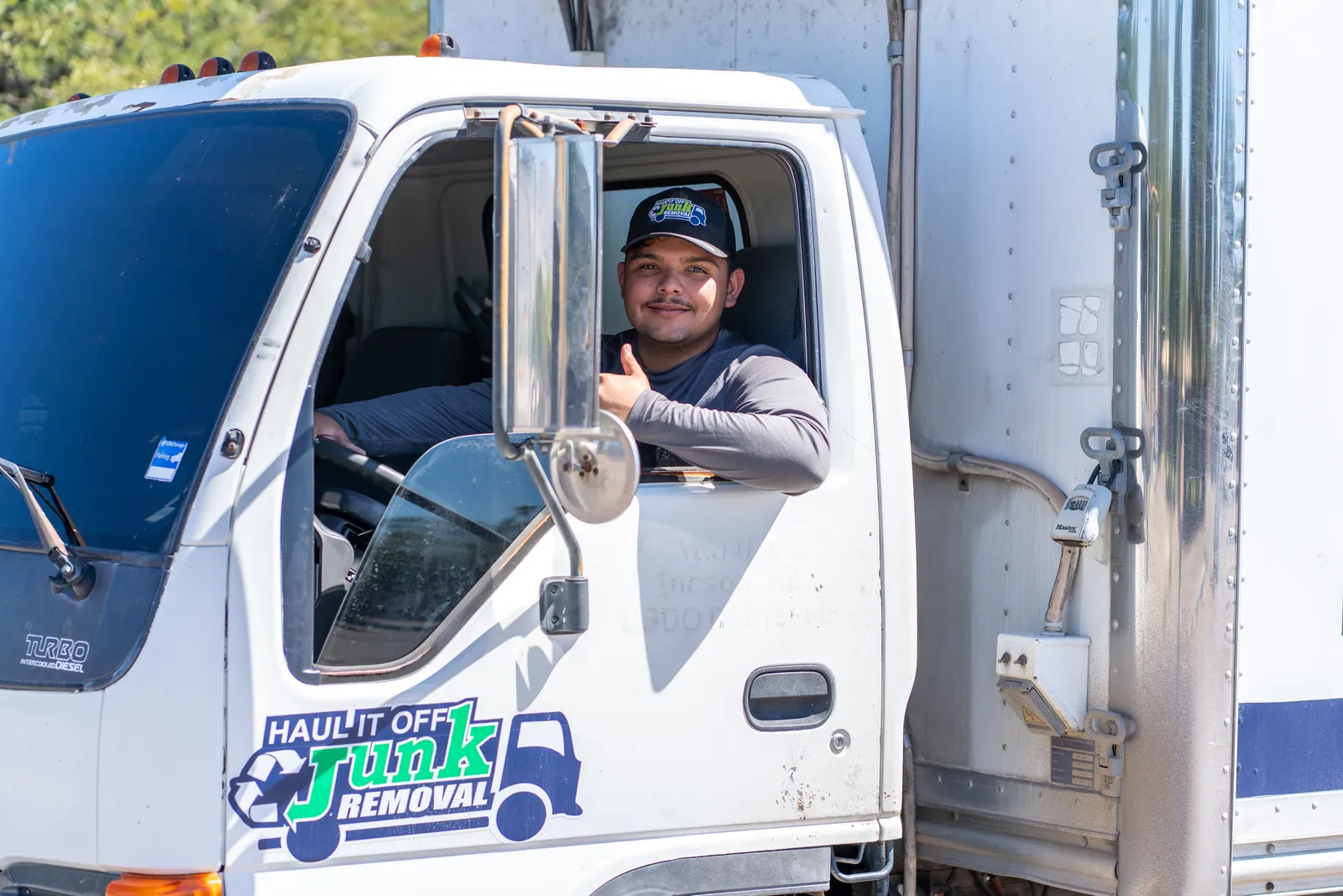 Haul It Off driver giving a thumbs-up from the cab of the company truck