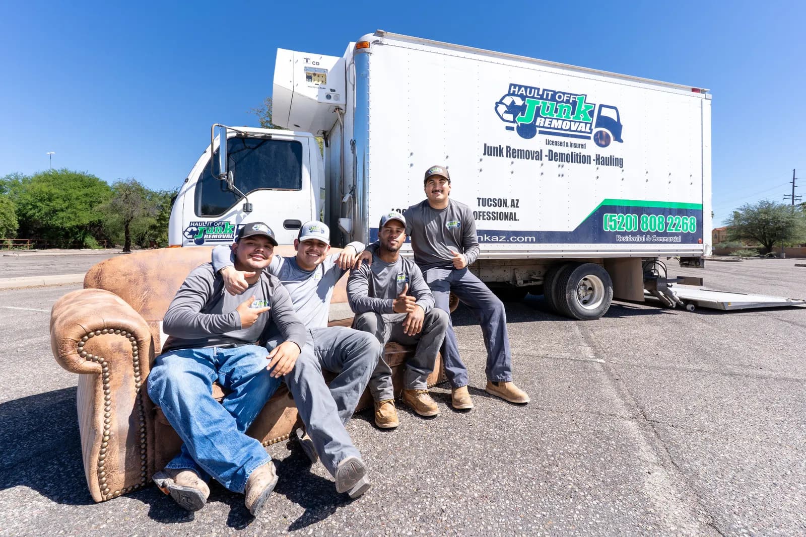 Haul It Off crew sitting on a leather couch in front of the company truck