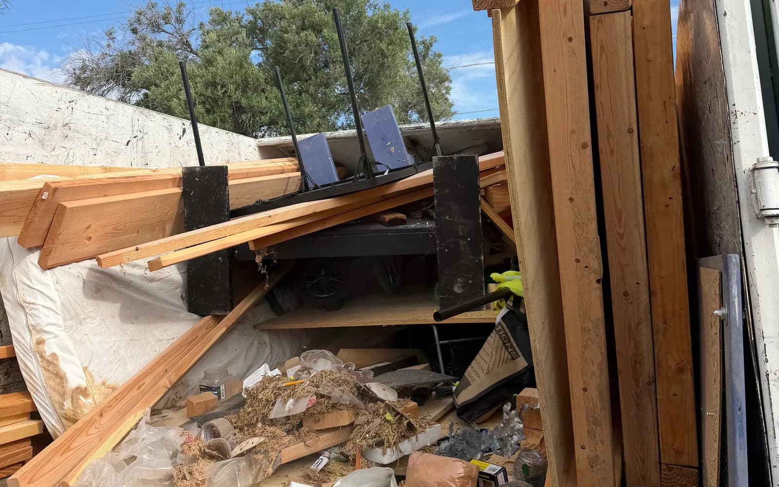 Truck bed loaded with lumber, a metal table and mixed debris